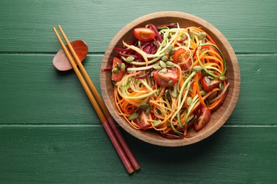 Photo of Tasty vegetable noodles served on green wooden table, top view