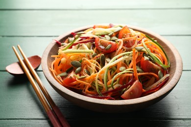 Photo of Tasty vegetable noodles served on green wooden table, closeup