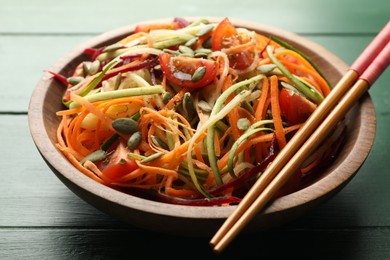 Photo of Tasty vegetable noodles served on green wooden table, closeup