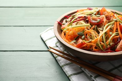 Photo of Tasty vegetable noodles served on green wooden table, closeup. Space for text