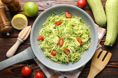 Photo of Tasty zucchini noodles with tomatoes, thyme and ingredients on wooden table, flat lay