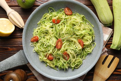 Photo of Tasty zucchini noodles with tomatoes, thyme and ingredients on wooden table, flat lay