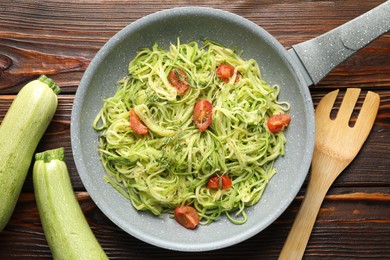 Photo of Tasty zucchini noodles with tomatoes and thyme on wooden table, flat lay