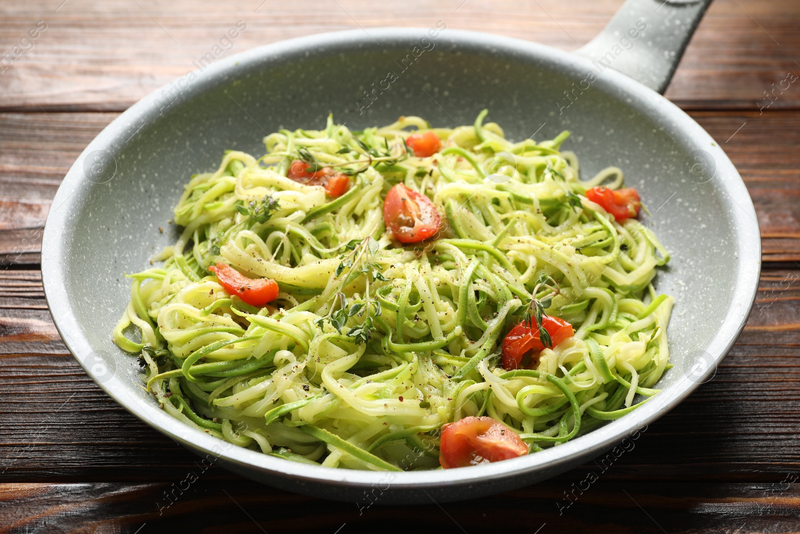 Tasty zucchini noodles with tomatoes and thyme on wooden table, closeup Photo of Tasty zucchini noodles with tomatoes and thyme on wooden table, closeup