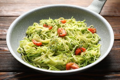 Photo of Tasty zucchini noodles with tomatoes and thyme on wooden table, closeup