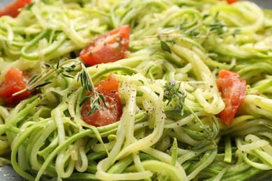 Photo of Tasty zucchini noodles with tomatoes and thyme, closeup