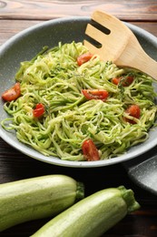 Photo of Tasty zucchini noodles with tomatoes and thyme on wooden table, closeup