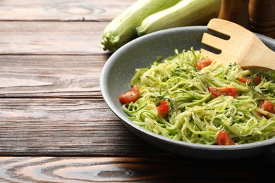 Photo of Tasty zucchini noodles with tomatoes and thyme on wooden table, closeup. Space for text