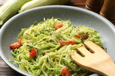 Photo of Tasty zucchini noodles with tomatoes and thyme on wooden table, closeup