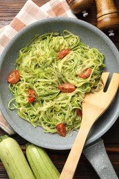 Photo of Tasty zucchini noodles with tomatoes, thyme and ingredients on wooden table, flat lay