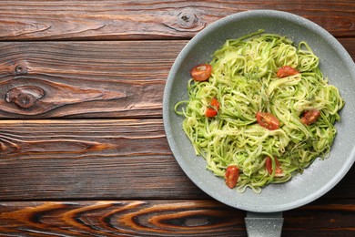 Photo of Tasty zucchini noodles with tomatoes and thyme on wooden table, top view. Space for text