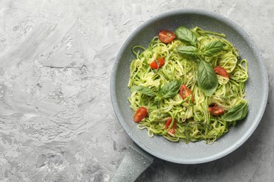 Photo of Tasty zucchini noodles with tomatoes and basil on grey table, top view. Space for text
