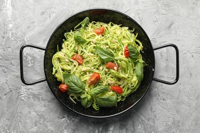 Photo of Tasty zucchini noodles with tomatoes, pine nuts and basil on grey table, top view