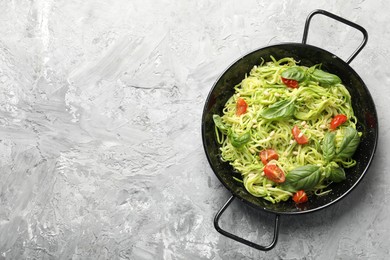 Photo of Tasty zucchini noodles with tomatoes, pine nuts and basil on grey table, top view. Space for text