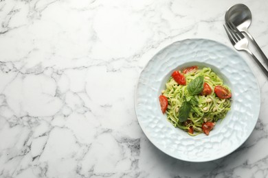 Photo of Tasty zucchini noodles with tomatoes, pine nuts and basil served on white marble table, top view. Space for text