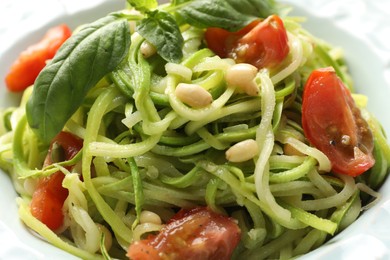 Photo of Tasty zucchini noodles with tomatoes, pine nuts and basil, closeup