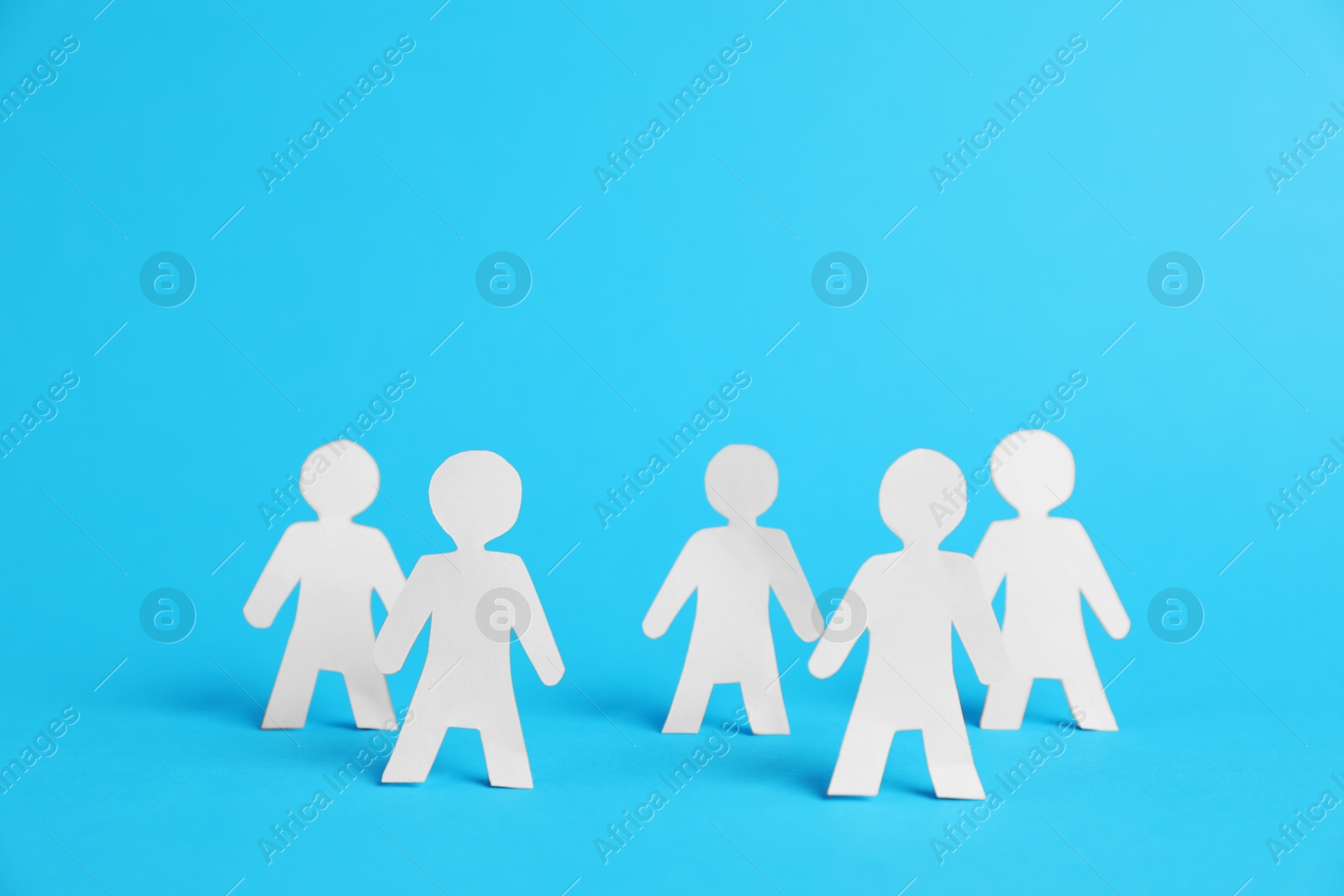 Human paper figures on light blue background Photo of Human paper figures on light blue background