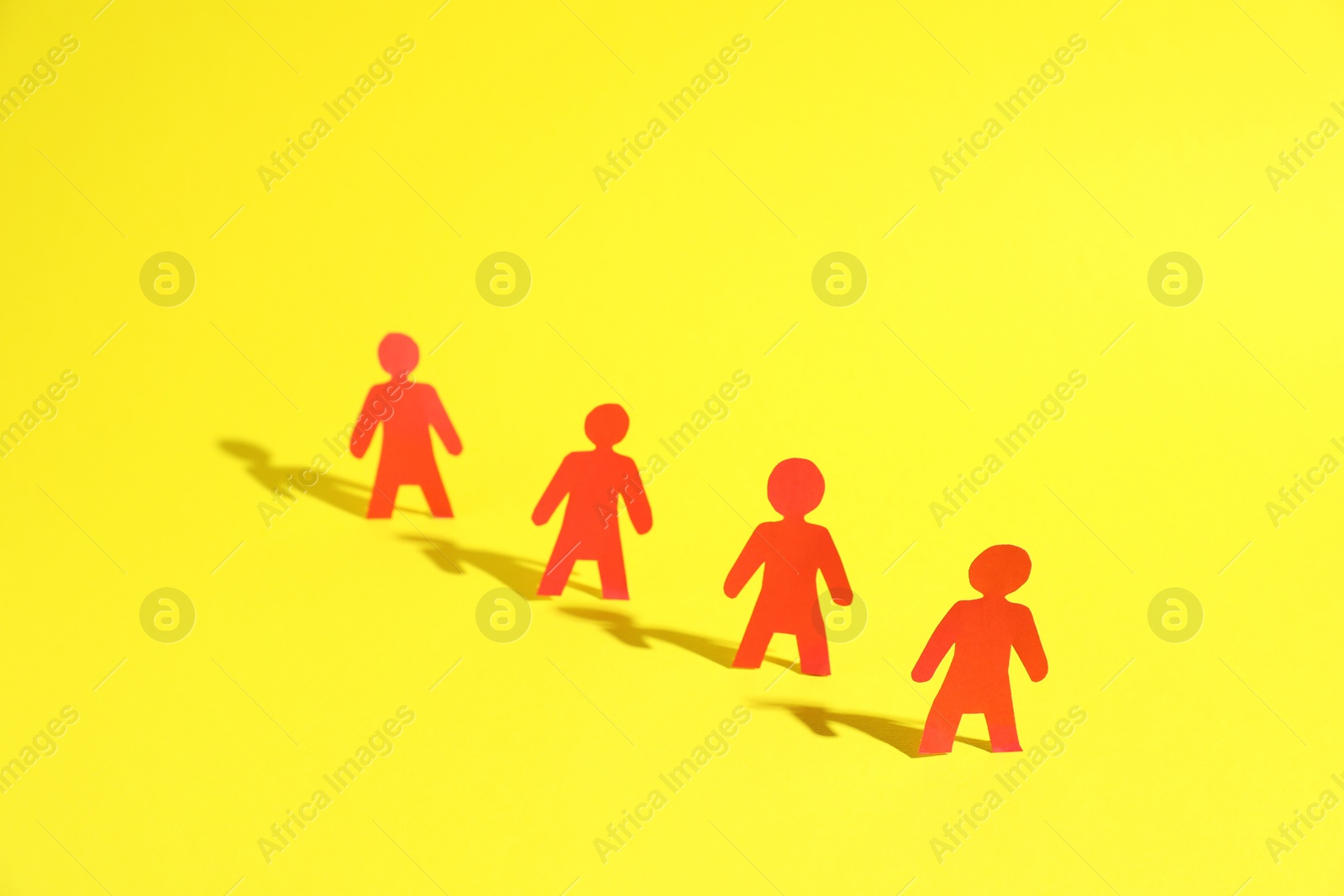 Photo of Many human paper figures on yellow background. Space for text