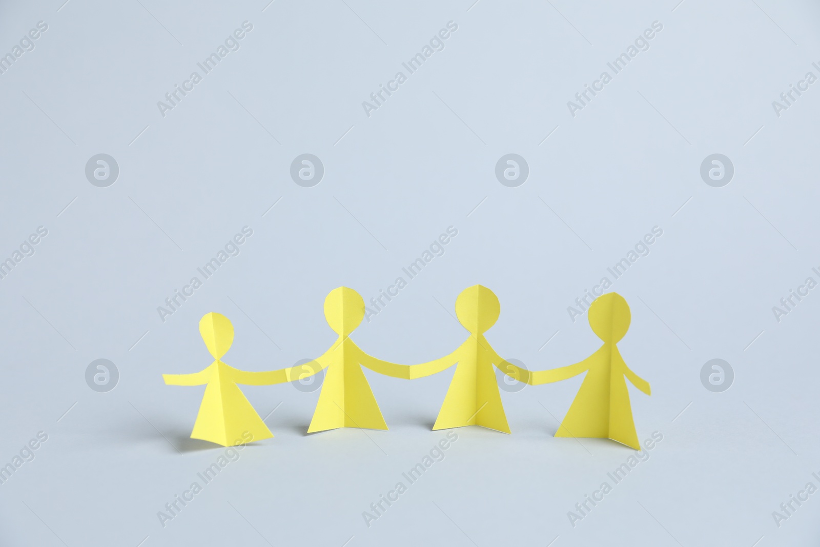 Human paper figures holding hands on light background Photo of Human paper figures holding hands on light background
