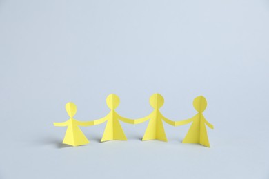Photo of Human paper figures holding hands on light background
