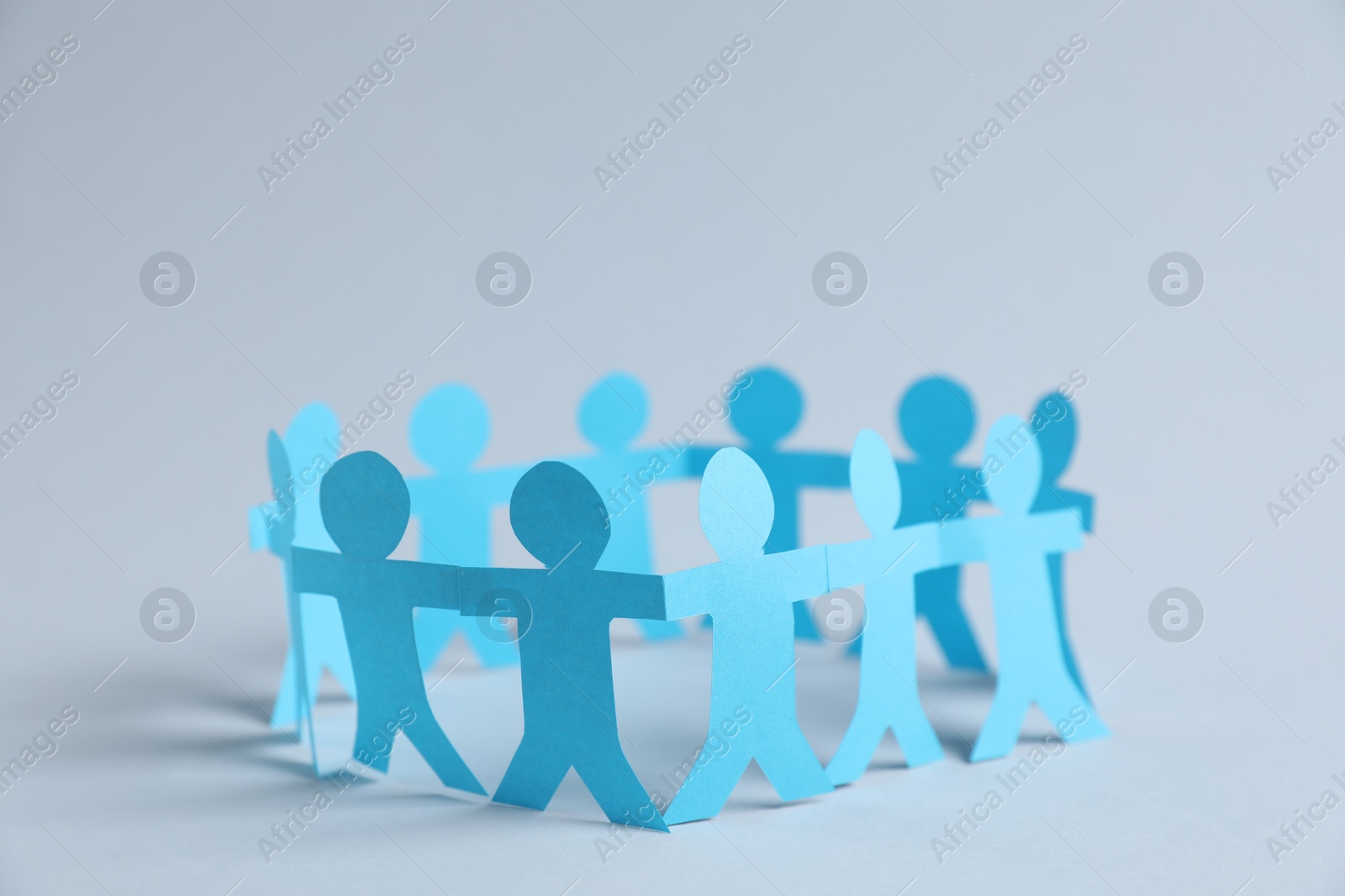 Human paper figures holding hands on light background Photo of Human paper figures holding hands on light background