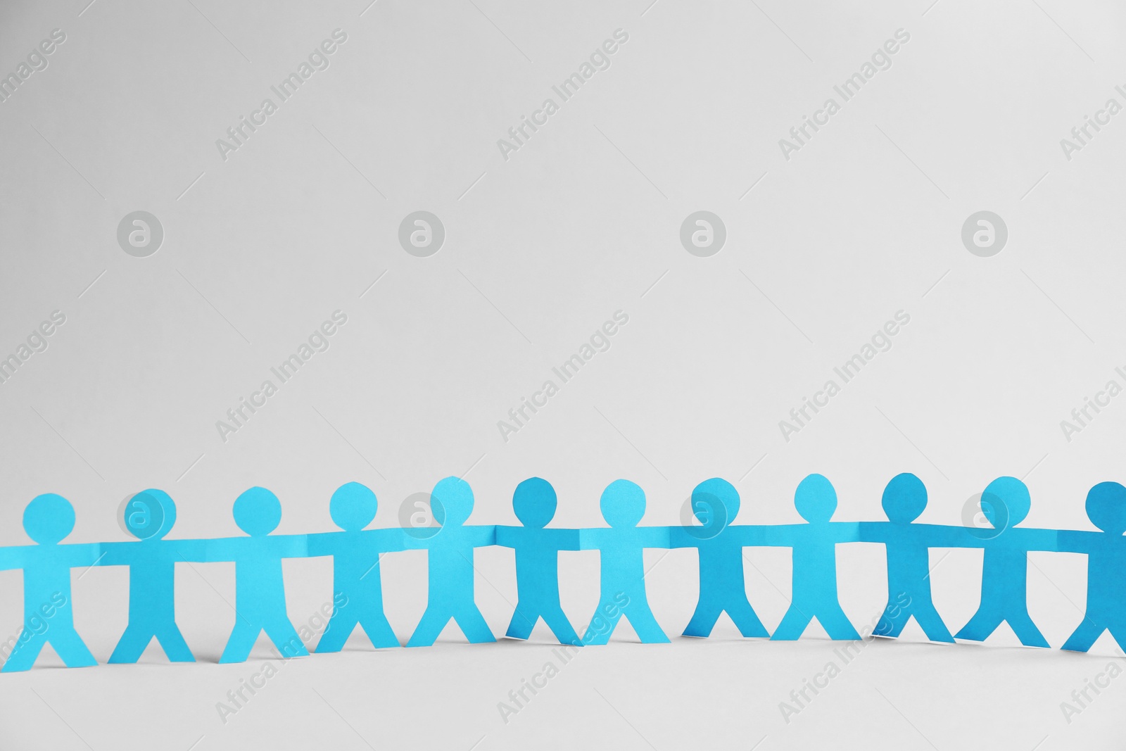 Human paper figures holding hands on light background. Space for text Photo of Human paper figures holding hands on light background. Space for text