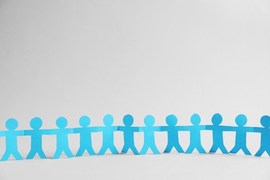 Photo of Human paper figures holding hands on light background. Space for text