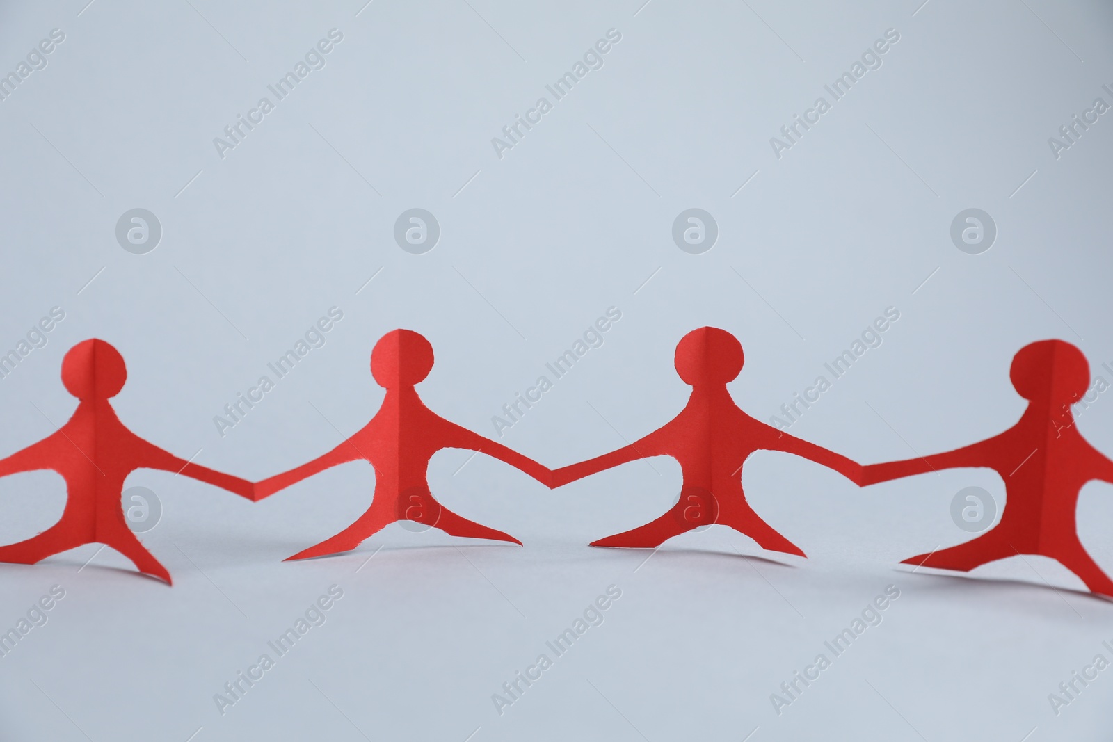 Photo of Human paper figures holding hands on light background