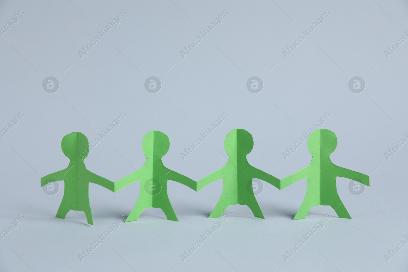 Photo of Human paper figures holding hands on light background