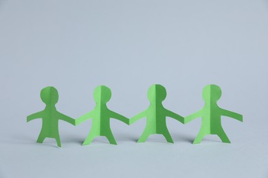 Photo of Human paper figures holding hands on light background