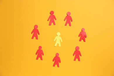 Photo of Many human paper figures on orange background, flat lay