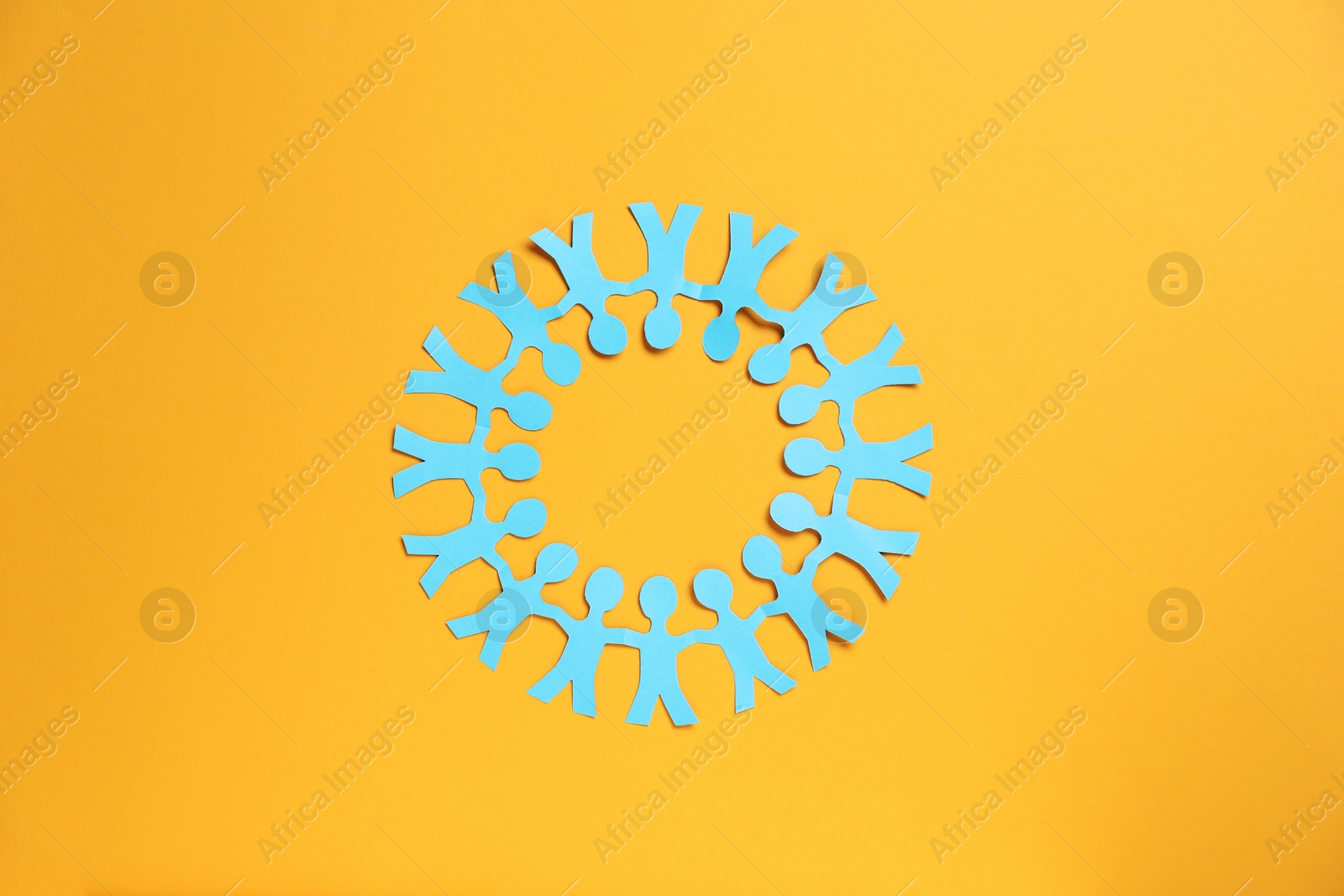Human paper figures holding hands on orange background, top view Photo of Human paper figures holding hands on orange background, top view