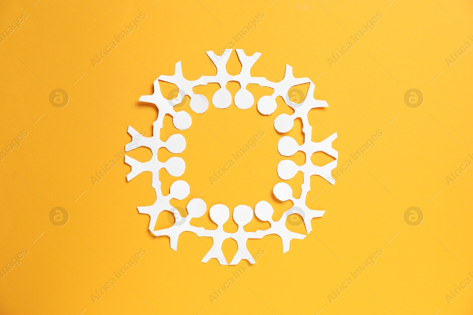 Human paper figures holding hands on orange background, top view Photo of Human paper figures holding hands on orange background, top view