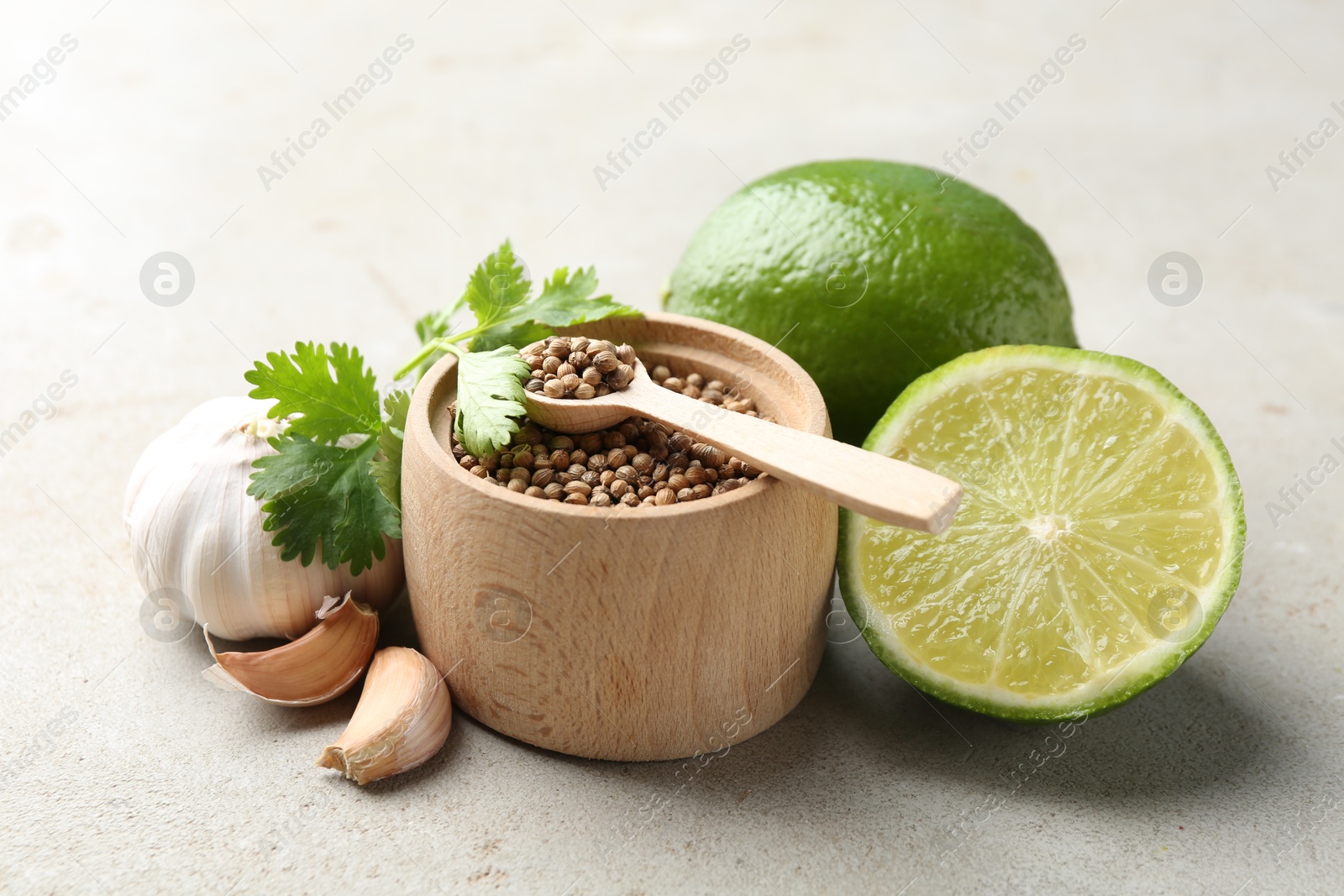 Photo of Coriander seeds, fresh cilantro, lime and garlic on light textured table, closeup