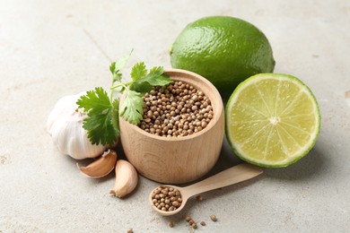 Photo of Coriander seeds, fresh cilantro, lime and garlic on light textured table, closeup