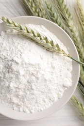 Photo of Green wheat spikes and flour on light table, flat lay