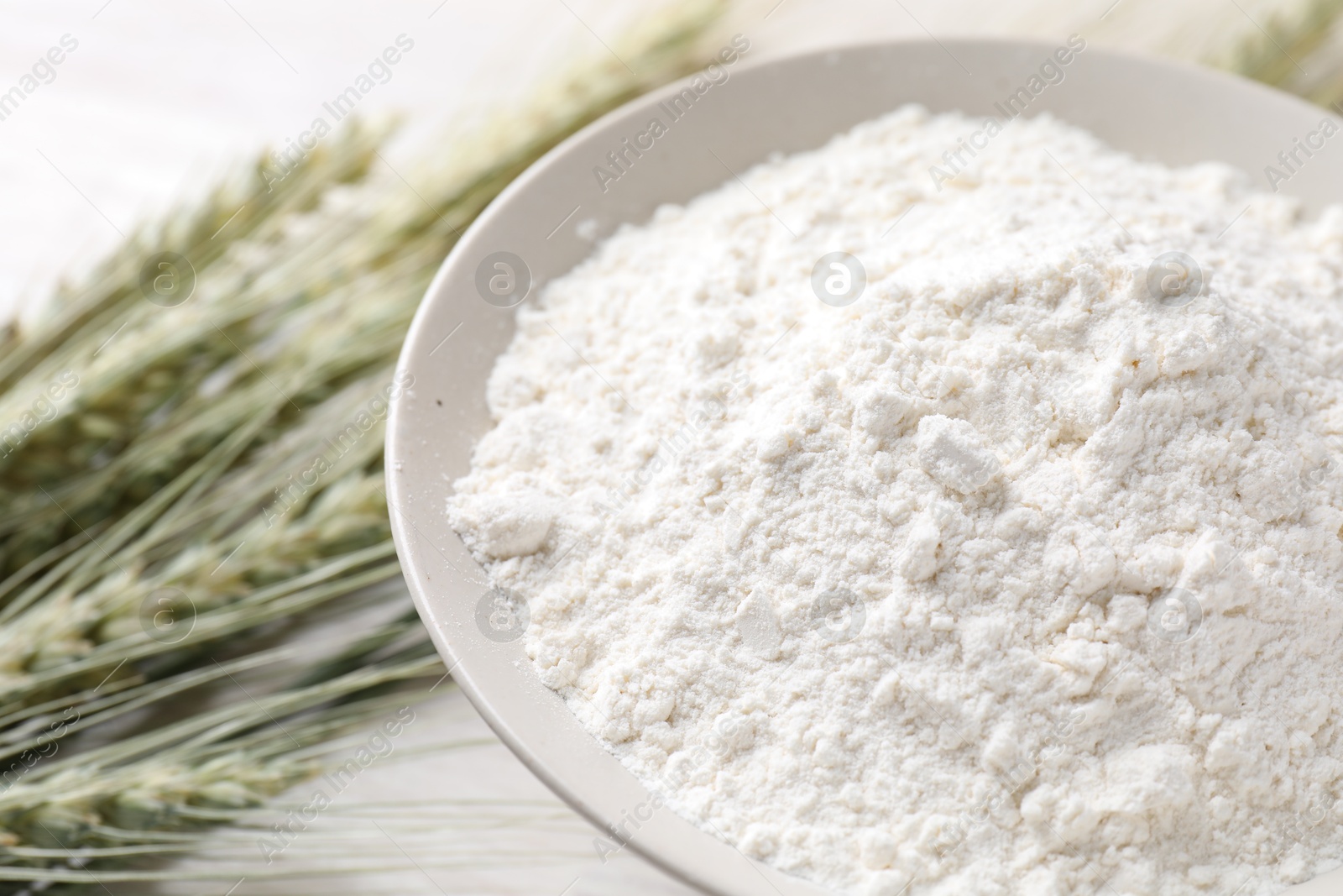 Green wheat spikes and flour on light table, closeup Photo of Green wheat spikes and flour on light table, closeup