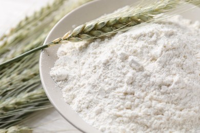 Photo of Green wheat spikes and flour on table, closeup