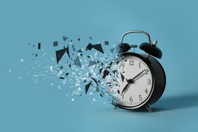 Image of Time running out. Black alarm clock dissolving against light blue background