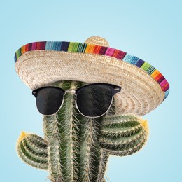Image of Cactus with sunglasses and sombrero hat against light blue background