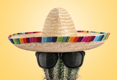 Image of Cactus with sunglasses and sombrero hat against pale orange background