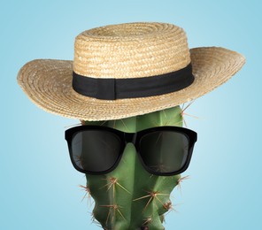 Image of Cactus with sunglasses and hat against light blue background