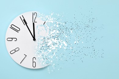 Image of Time running out. Clock dissolving on light blue background