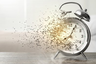Image of Time running out. Silver alarm clock dissolving on table
