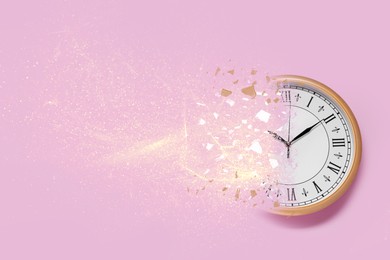 Image of Time running out. Clock dissolving on pink background