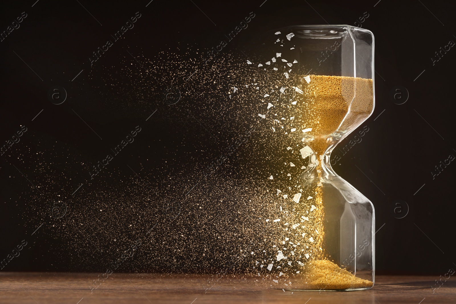 Image of Time running out. Hourglass dissolving on table against black background