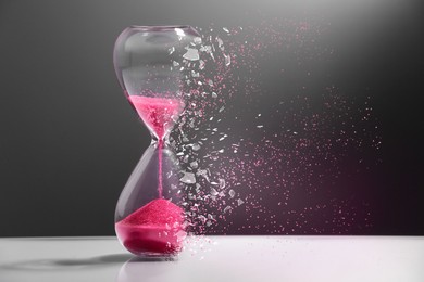 Image of Time running out. Hourglass dissolving on table against dark background