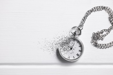 Image of Time running out. Pocket watch dissolving on white table, top view