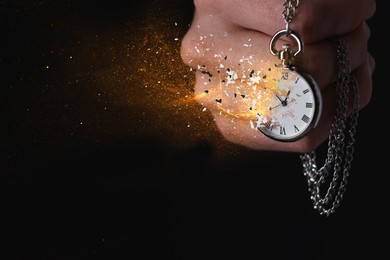 Image of Time running out. Pocket watch dissolving in man's hand against black background, closeup