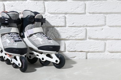 Photo of Pair of roller skates on grey marble table near white brick wall, closeup. Space for text